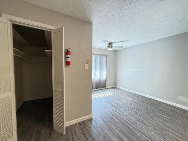 an empty room with wooden floor closet and windows