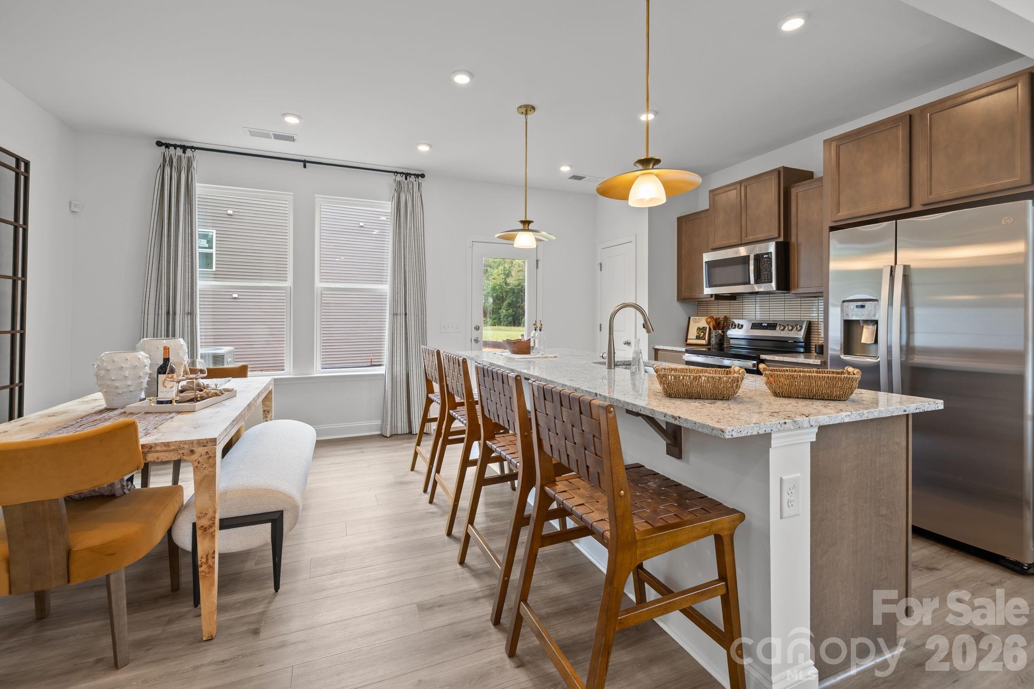 7709 Ethora Way Charlotte, NC 28216 - Photo 12 of 33 a kitchen with stainless steel appliances kitchen island granite countertop a sink a stove a refrigerator and island with wooden floor