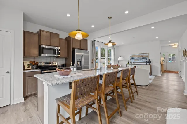 a kitchen with stainless steel appliances kitchen island granite countertop a stove a sink a dining table and chairs