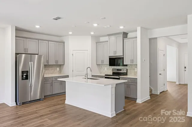 a kitchen with stainless steel appliances granite countertop a refrigerator stove top oven and sink