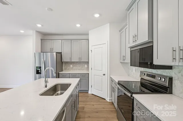 a kitchen with stainless steel appliances granite countertop a sink stove and refrigerator