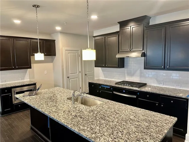 a large kitchen with granite countertop a sink and a stove