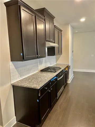 a view of an empty room with a window and a kitchen