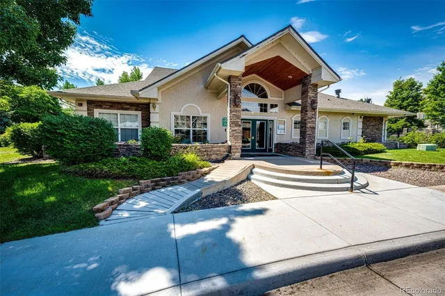 a front view of a house with a yard outdoor seating and mountain view in back
