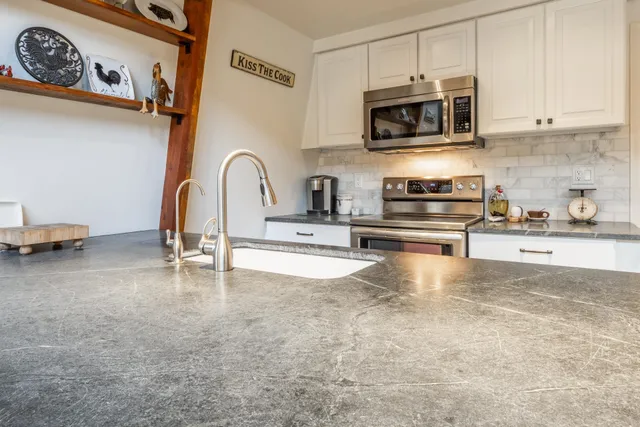 a kitchen with stainless steel appliances granite countertop a stove and a microwave with cabinets