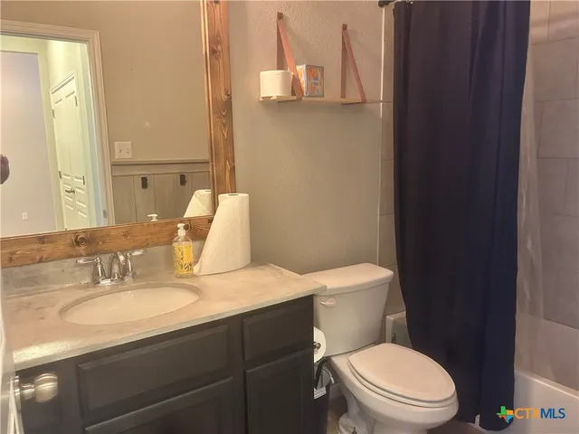 a bathroom with a granite countertop toilet sink and mirror