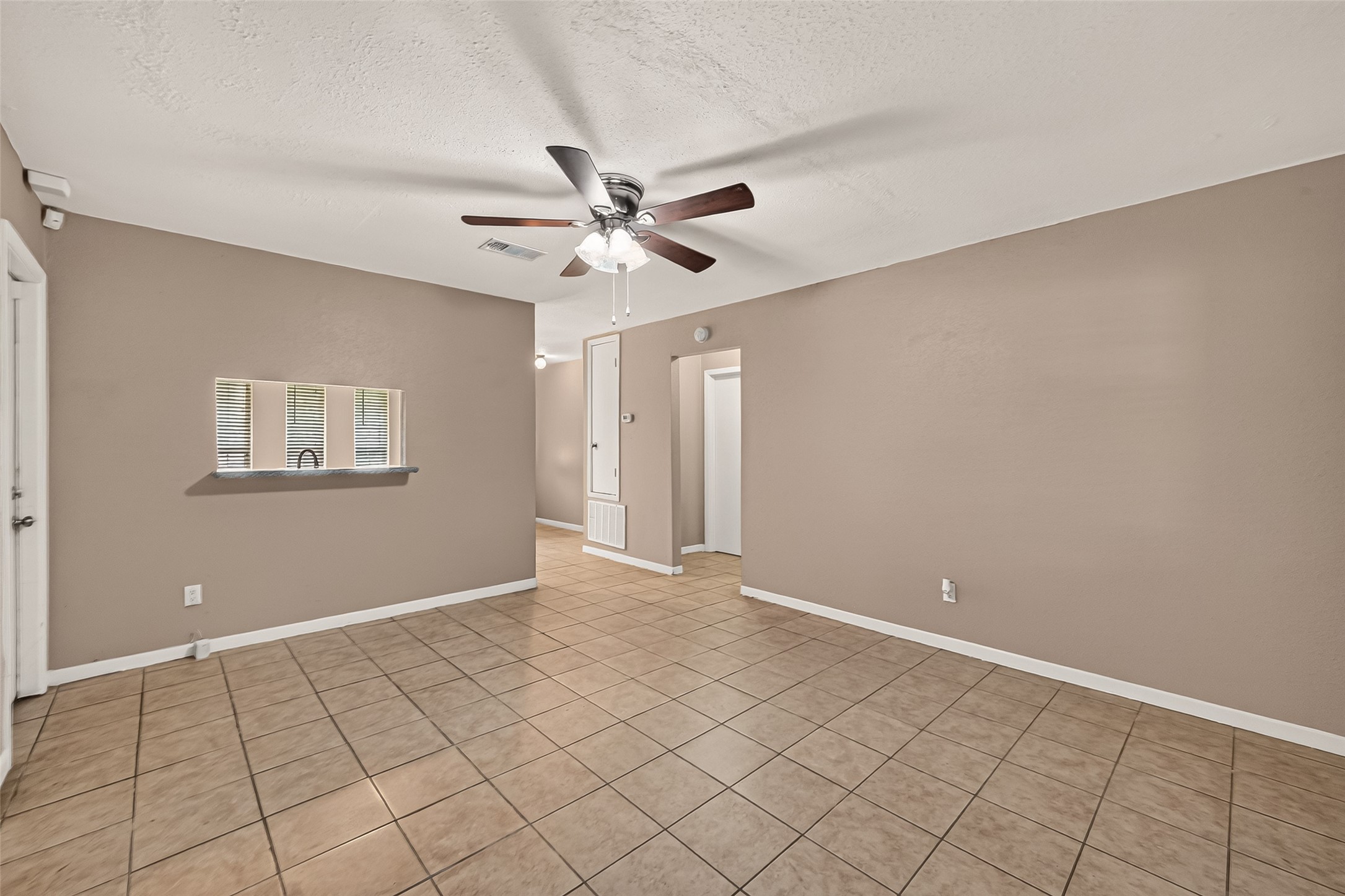 719 Kilpatrick Street Channelview, TX 77530 - Photo 12 of 40 The kitchen and living area connect seamlessly, creating an easy flow for entertaining. The spacious living room features tile flooring and a ceiling fan for added comfort.