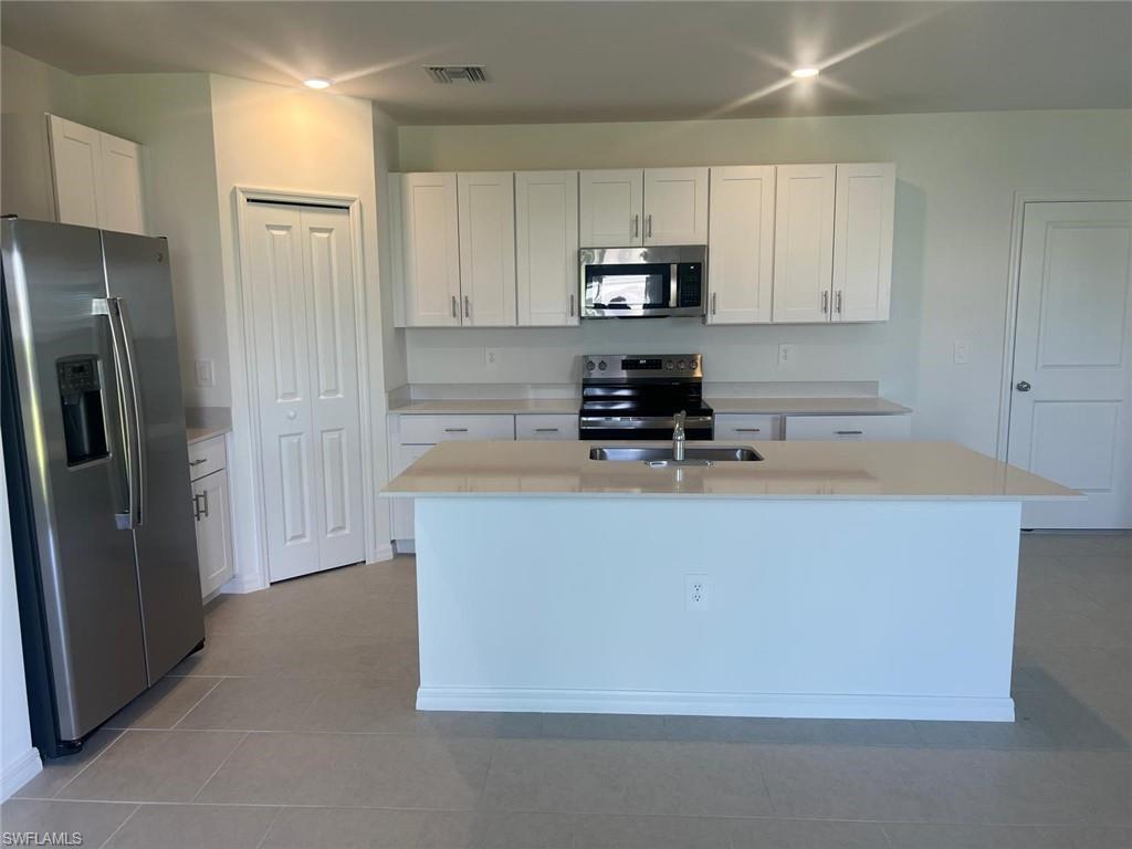 19763 Garden Rdg Court Lehigh Acres, FL 33936 - Photo 2 of 12 a kitchen with stainless steel appliances a refrigerator a stove a sink and white cabinets