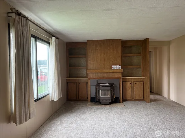 an empty room with a fireplace cabinet and window