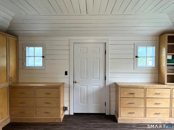an empty room with wooden floor closet and windows