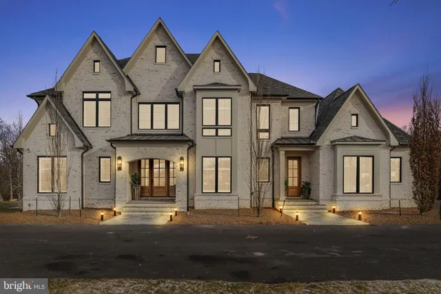 a view of a white house next to a yard with large trees