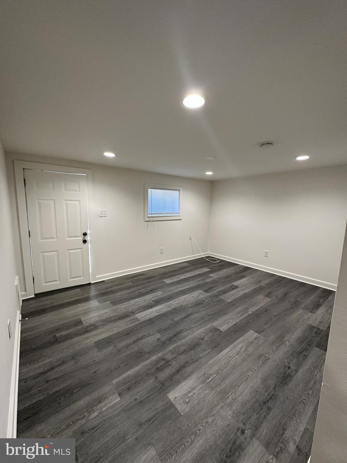an empty room with wooden floor and window