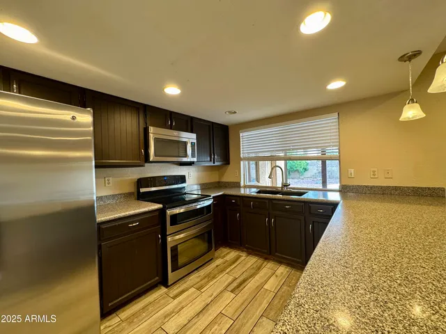 a kitchen with stainless steel appliances granite countertop a stove a sink and a refrigerator