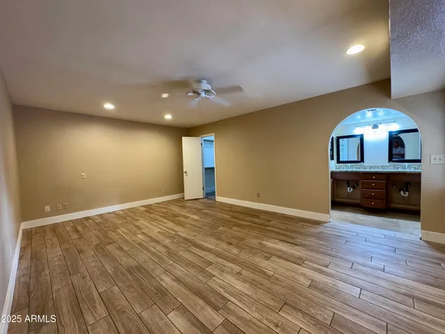 a view of an empty room with wooden floor and a kitchen