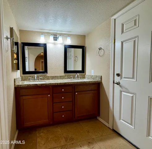 a bathroom with a granite countertop double vanity sink and a mirror