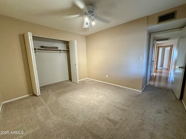 an empty room with closet and a ceiling fan