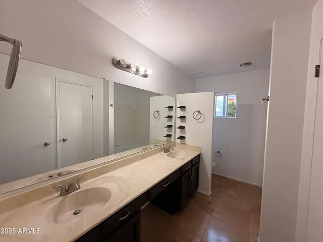 a bathroom with a sink double vanity granite tub shower and a mirror