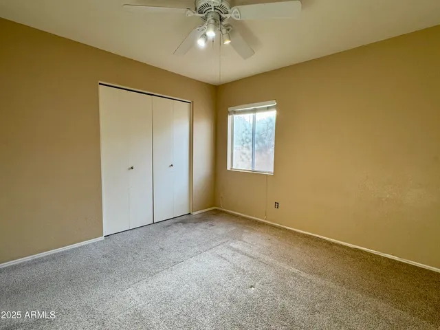 an empty room with a chandelier fan and windows