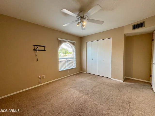 an empty room with windows and ceiling fan