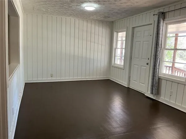 an empty room with wooden floor and windows with curtains