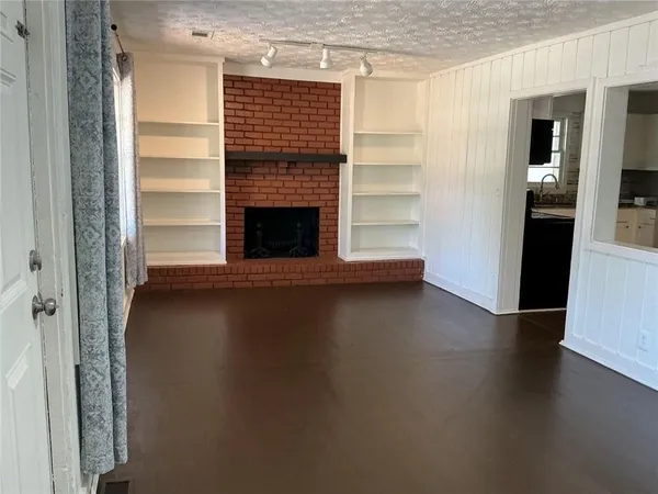 an empty room with wooden floor fireplace and windows