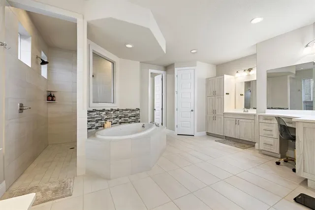 a bathroom with a tub sink shower and mirror