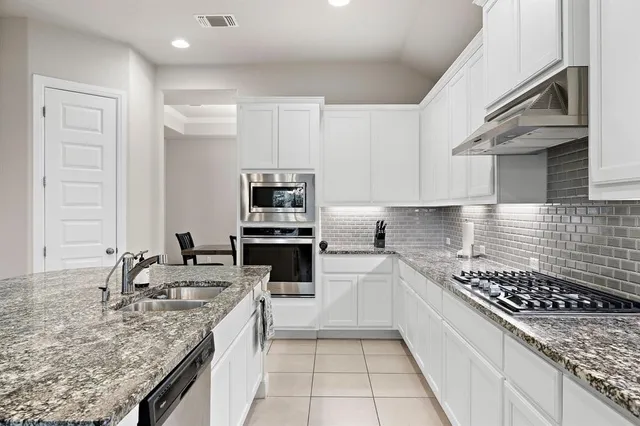 a kitchen with stainless steel appliances granite countertop a sink stove and cabinets