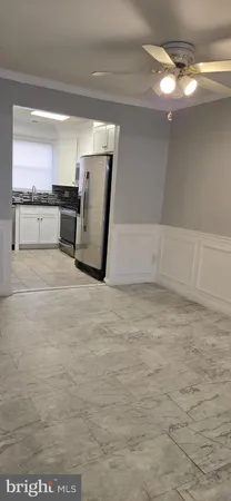 a view of a refrigerator in kitchen and an empty room
