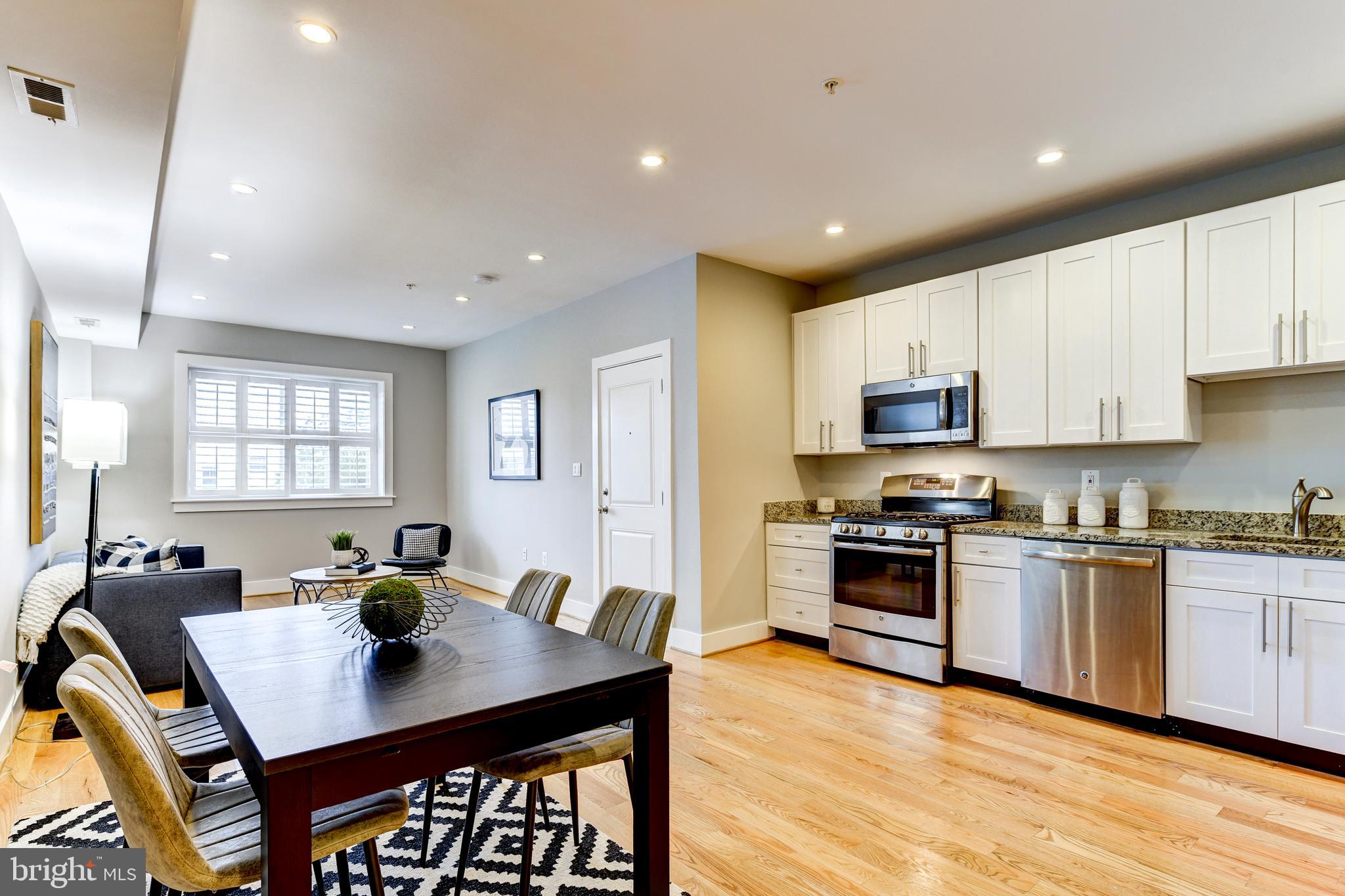 1928 3rd Street Northeast, Unit 2 Washington, DC 20002 - Photo 11 of 20 a open kitchen with stainless steel appliances granite countertop a stove refrigerator a sink dishwasher a dining table and chairs with wooden floor