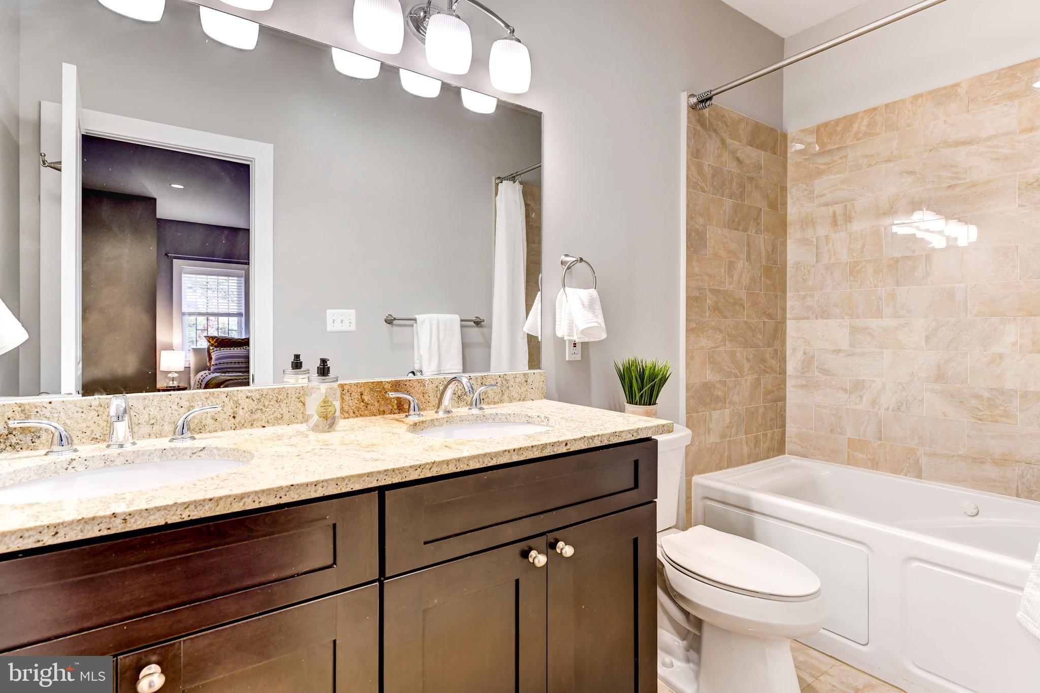 1928 3rd Street Northeast, Unit 2 Washington, DC 20002 - Photo 16 of 20 a bathroom with a granite countertop sink a toilet a mirror a bathtub and shower