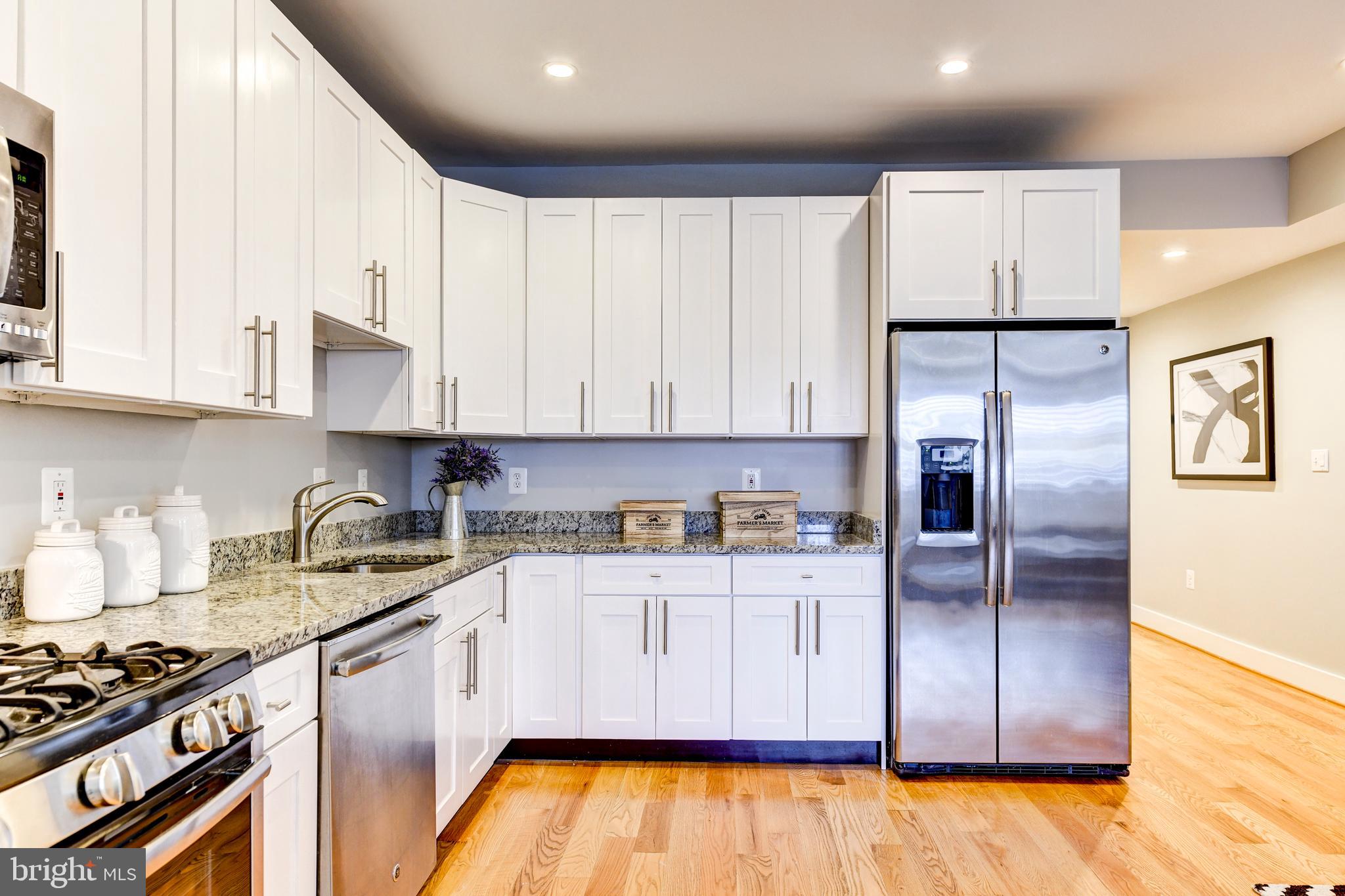 1928 3rd Street Northeast, Unit 2 Washington, DC 20002 - Photo 9 of 20 a kitchen with granite countertop a refrigerator a sink and wooden cabinets