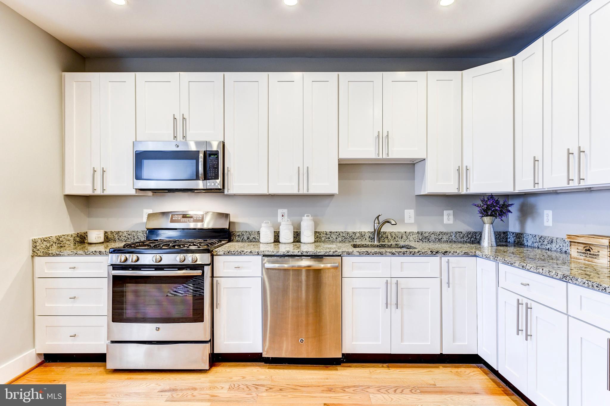 1928 3rd Street Northeast, Unit 2 Washington, DC 20002 - Photo 10 of 20 a kitchen with granite countertop white cabinets and stainless steel appliances