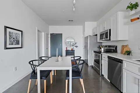 a kitchen with stainless steel appliances granite countertop a stove a refrigerator a dining table and chairs with wooden floor