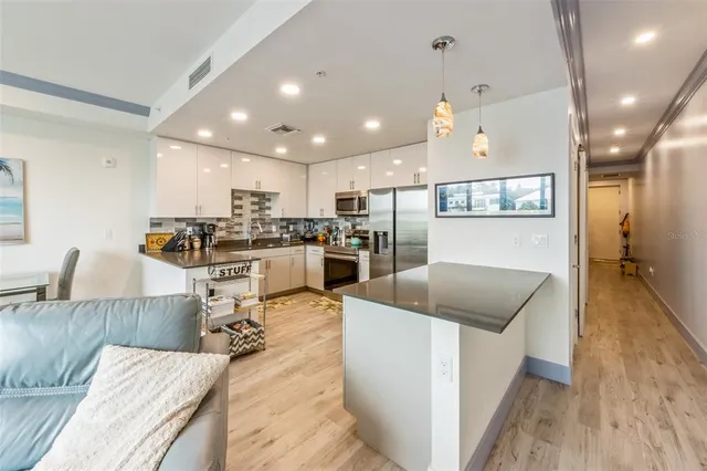a living room with stainless steel appliances furniture or kitchen view and a wooden floor