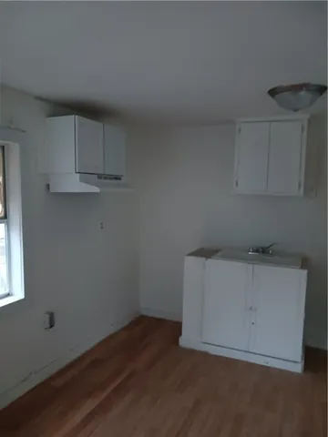 an empty room with wooden floor and cabinets