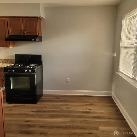 a kitchen with granite countertop a stove and a wooden floor