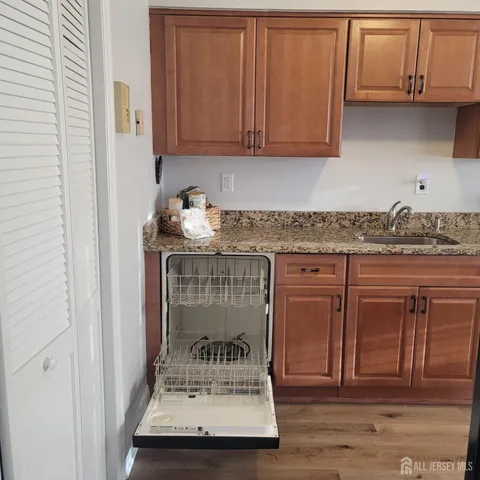a view of kitchen with granite countertop wooden cabinets