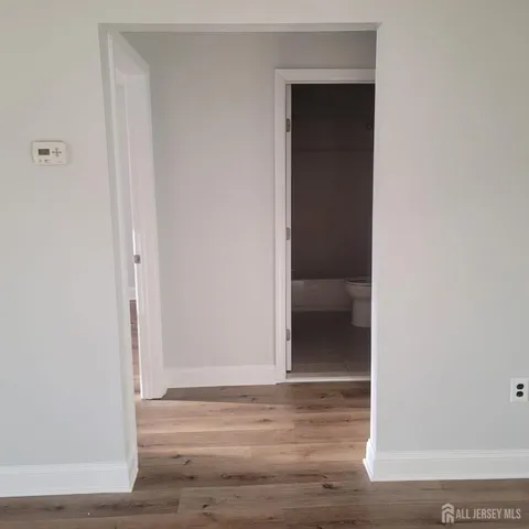 a view of an empty room with wooden floor & closet