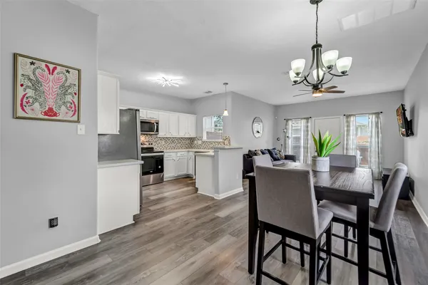 a view of a dining room and livingroom with furniture wooden floor a chandelier