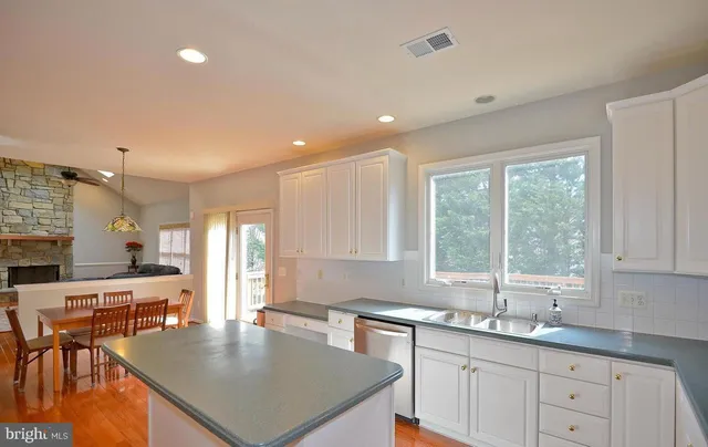 a kitchen with stainless steel appliances granite countertop a stove a sink a microwave a dining table and chairs