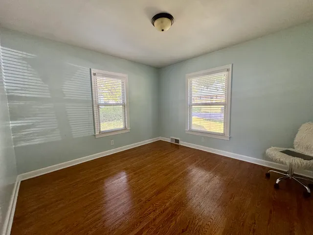 a view of an empty room with a window and wooden floor