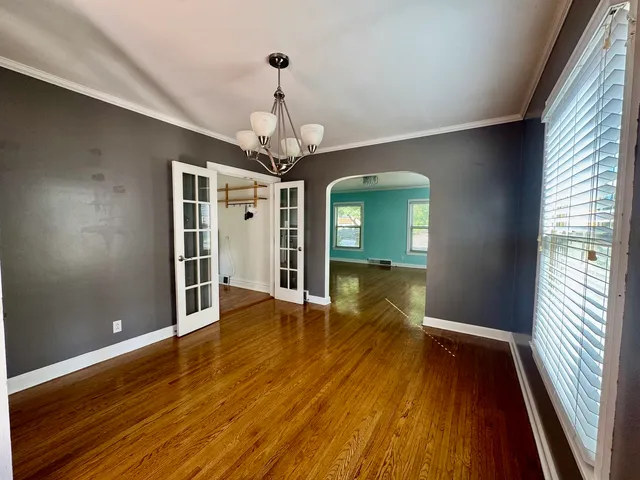 a view of a hallway with wooden floor and chandelier