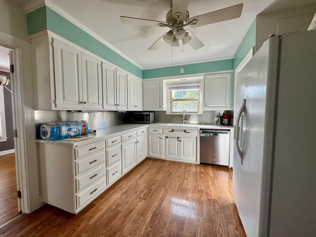 a kitchen with stainless steel appliances a sink cabinets and wooden floor