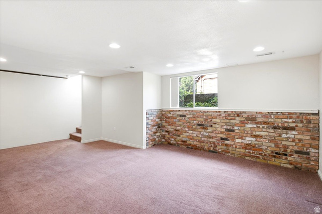 1341 29th Street Ogden, UT 84403 - Photo 22 of 37 Spacious room featuring a brick accent wall, recessed lighting, and a large window