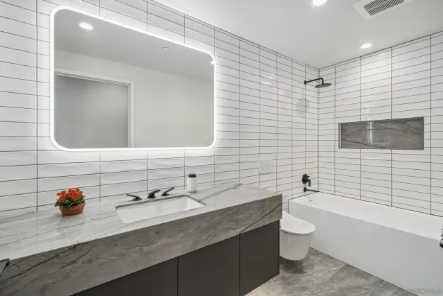 a bathroom with a granite countertop sink a mirror and shower