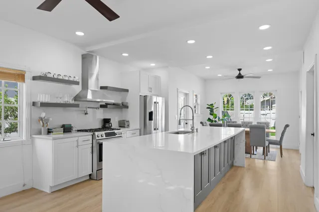 a kitchen with stainless steel appliances kitchen island granite countertop a table chairs refrigerator and sink