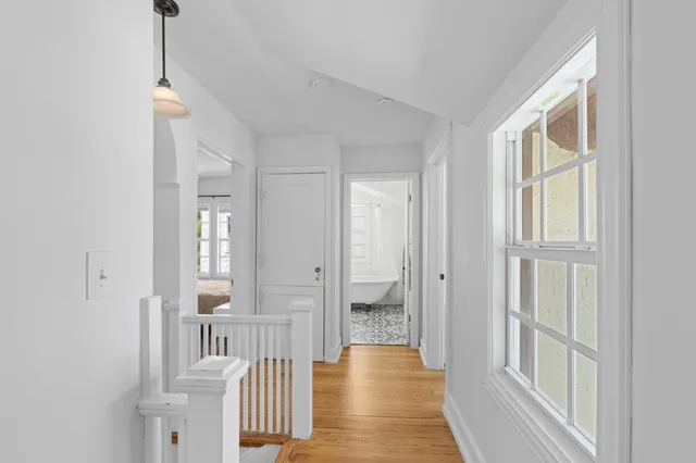 a view of a hallway with wooden floor and windows
