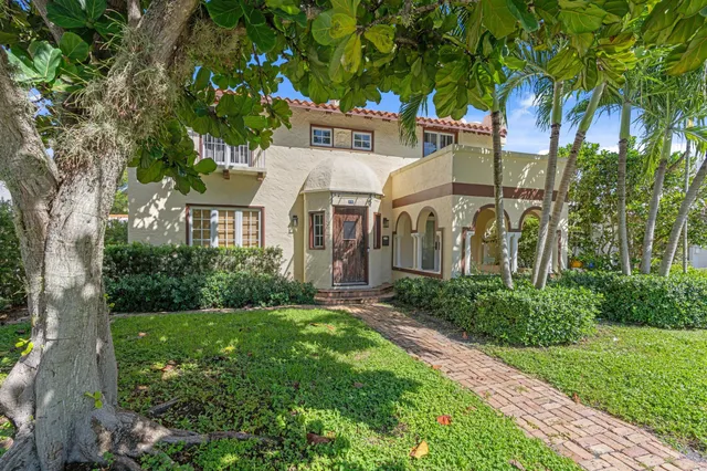 a view of a white house with a yard and potted plants