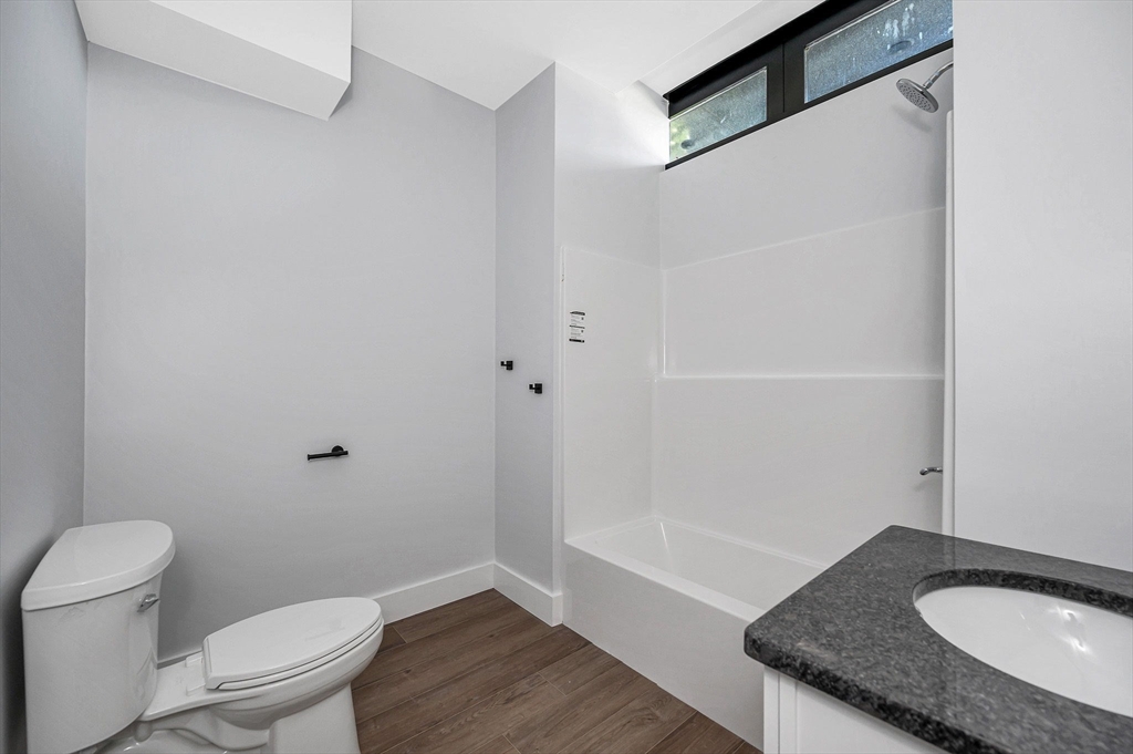 241 West 6th Street, Unit 102 Lowell, MA 01850 - Photo 11 of 25 a bathroom with a granite countertop sink toilet and a mirror