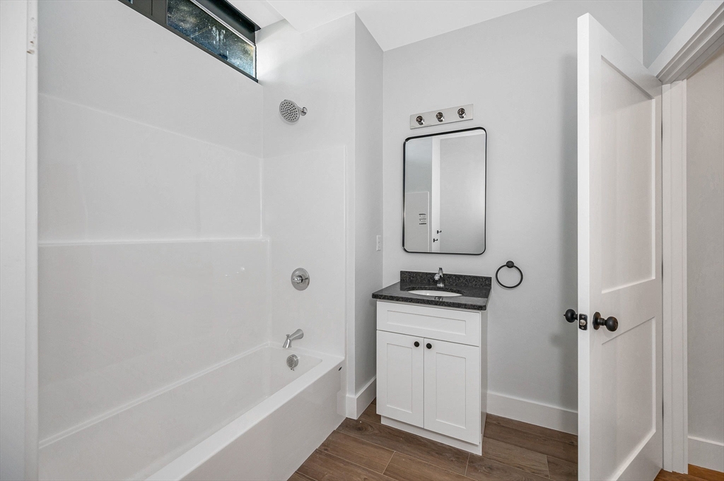 241 West 6th Street, Unit 102 Lowell, MA 01850 - Photo 12 of 25 a bathroom with a granite countertop sink a mirror and bathtub